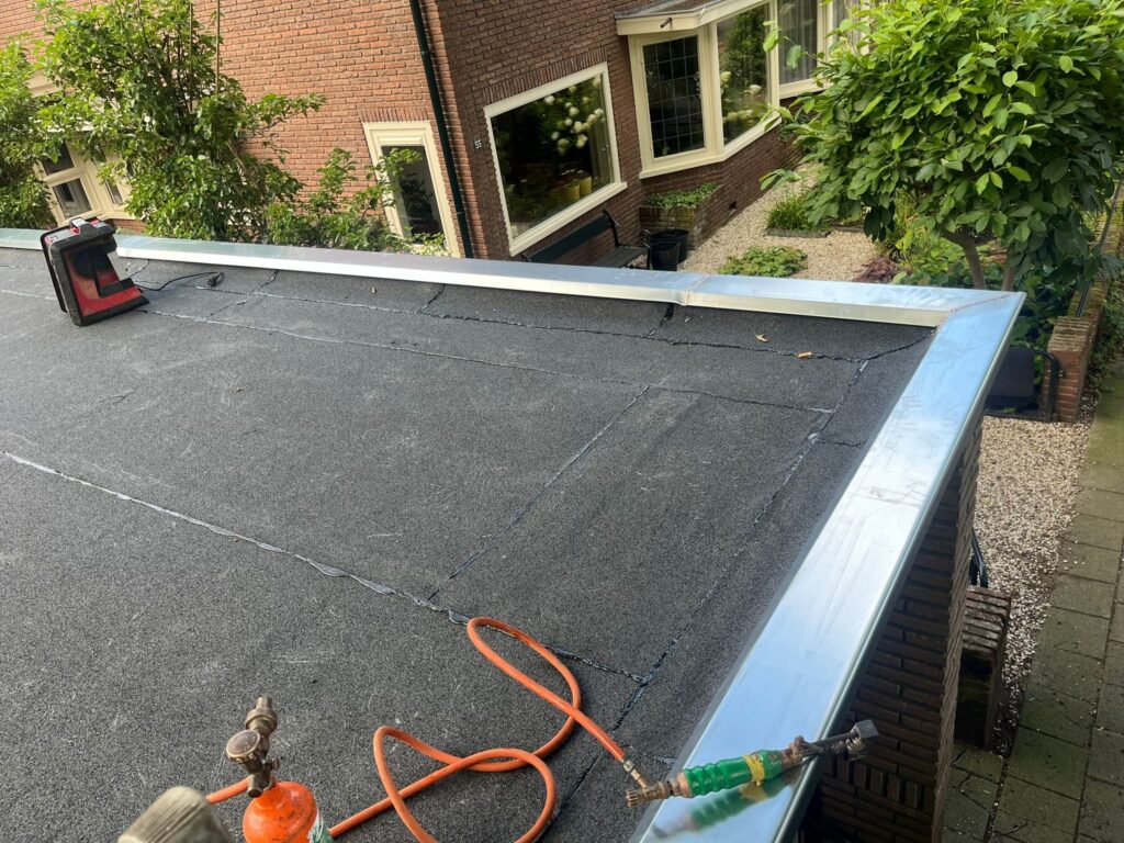 Dakoverlaging in Amersfoort met nieuwe bitumen dakbedekking en zinken deklijsten op een plat dak.
